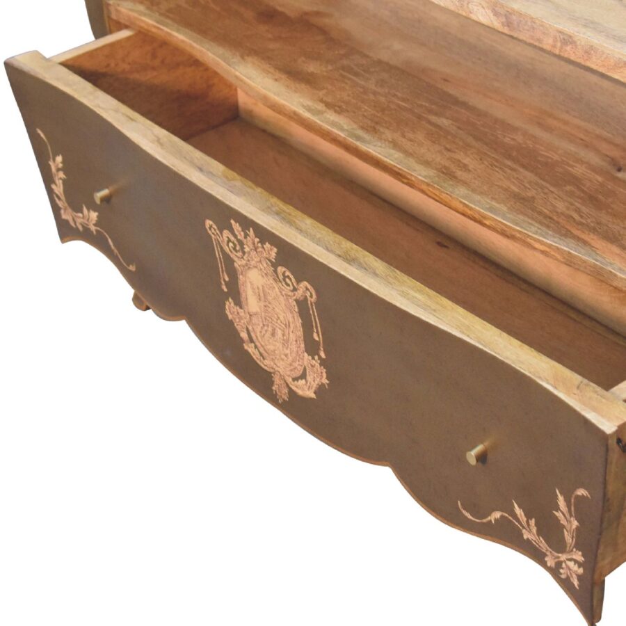 Open antique drawer with ornate emblem design.